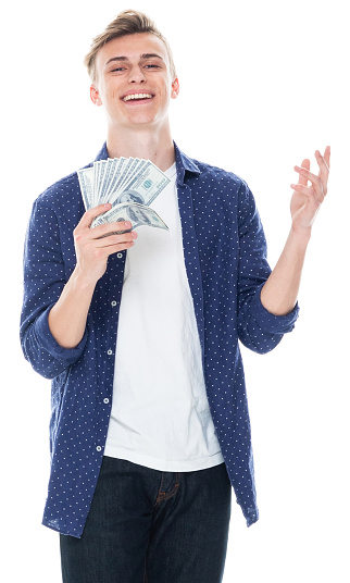 Front view of aged 16-17 years old with brown hair caucasian young male standing in front of white background wearing shirt who is showing cool attitude and holding currency