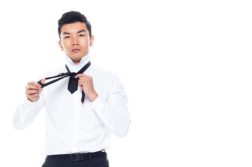 One person of aged 20-29 years old east asian ethnicity male business person standing in front of white background wearing necktie who is in concentration