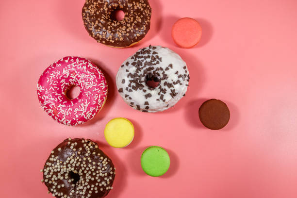 istock Tasty donuts and macaroons on pink background. Top view 1225438224