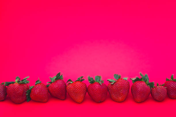 istock straberry in a row fruit pink background delicious red berry close-up 1225439128