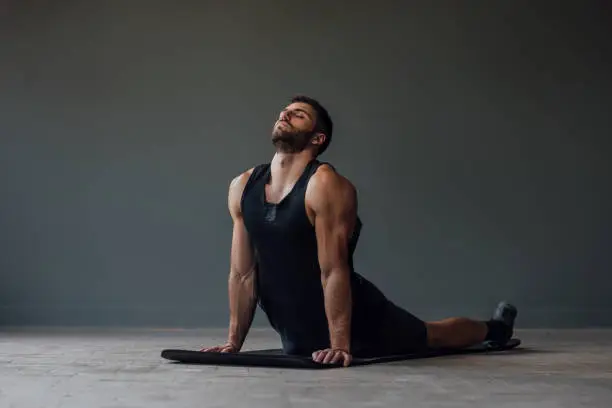 Man relaxing after a challenging workout by doing yoga.