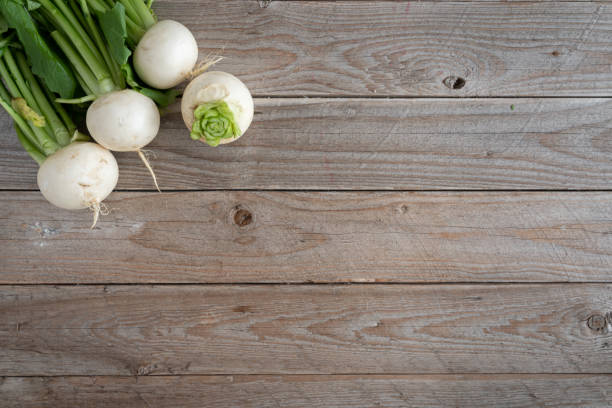 木製のテーブルの背景に白いカブの束。緑の葉とコピースペースを持つ新鮮なカブのトップビュー - turnip leaf vegetable green freshness ストックフォトと画像