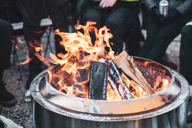 gruppe von freunden, die um ein feuer sitzen - feuer im freien stock-fotos und bilder