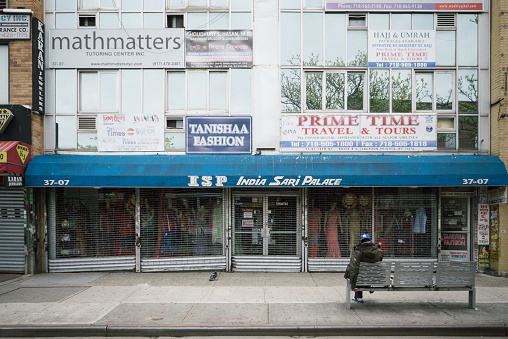 A man sits on a bench in front of a closed Indian clothing store in Jackson Heights, Queens. Jackson Heights is a lively South Asian and Latino neighborhood in the northwestern part of Queens heavily hit by the coronavirus. Queens is the largest borough in New York City and one of the most affected by COVID-19.