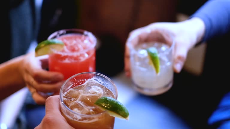 Friends cheers holding tropical blended fruit margaritas