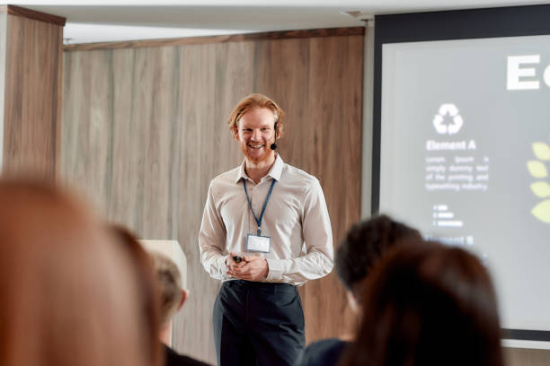 istock An institute for your future. Young male speaker in suit with headset and laser pointer smiling while giving a talk at business meeting, ecological forum 1225449301