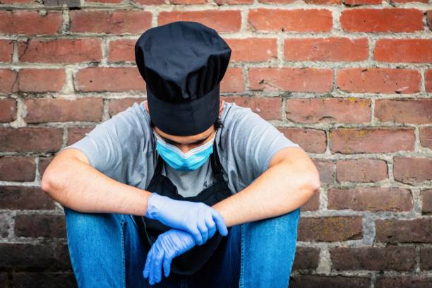 Young chef posing with a protective mask and gloves during a break looking down