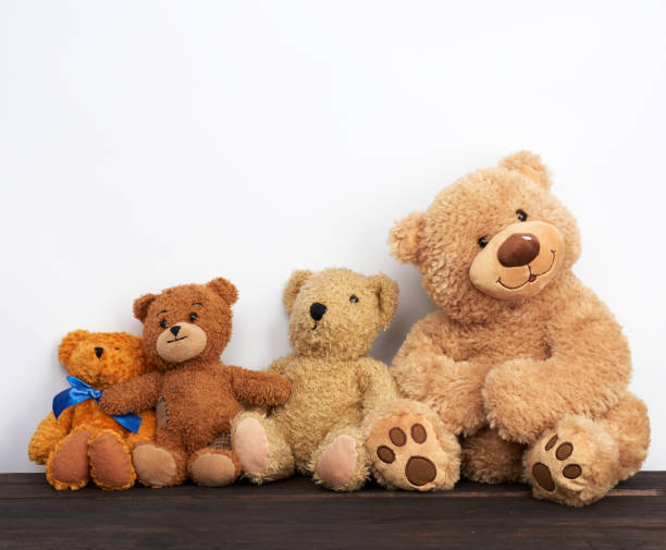 various brown teddy bears are sitting on a brown wooden table various brown teddy bears are sitting on a brown wooden table, white background, friendship concept behavior teddy bear doll old stock pictures, royalty-free photos & images