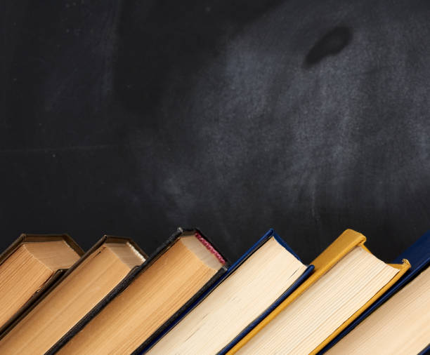 istock stack of various books on the background of an empty black chalk board 1225450353