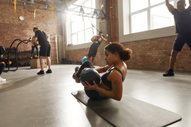 istock Fitness is my Outlook. Athletic young woman using a ball while having workout on a mat at industrial gym. Group training, teamwork concept 1225456325