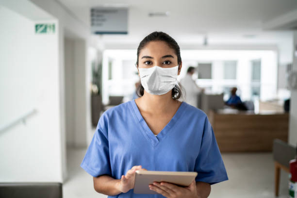 retrato de una enfermera que sostiene una tableta digital en el hospital con una máscara protectora - computer medical student hospital nurse fotografías e imágenes de stock