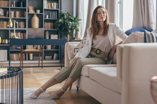 Woman in business attire after work at home resting on couch