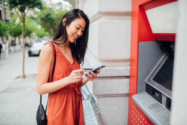 Beautiful Asian banking and shopping in the city Beautiful Asian girl taking the money from the ATM machine for shopping. atm photos stock pictures, royalty-free photos & images
