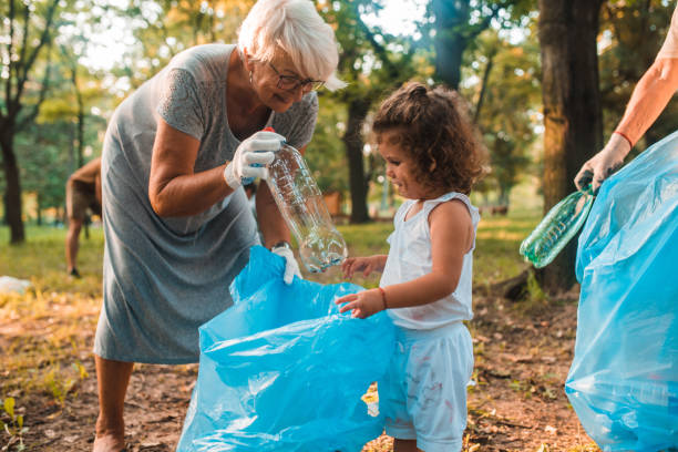 little girl cleaning the park with her grandma - sustainable resources environment education cleaning imagens e fotografias de stock