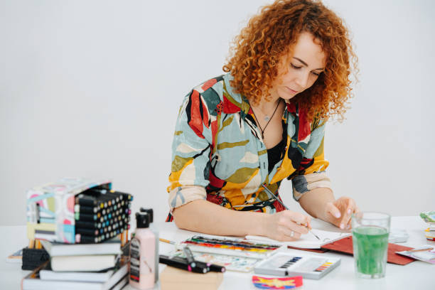 istock Focused artist painting with a brush on a messy cluttered workdesk 1225460244