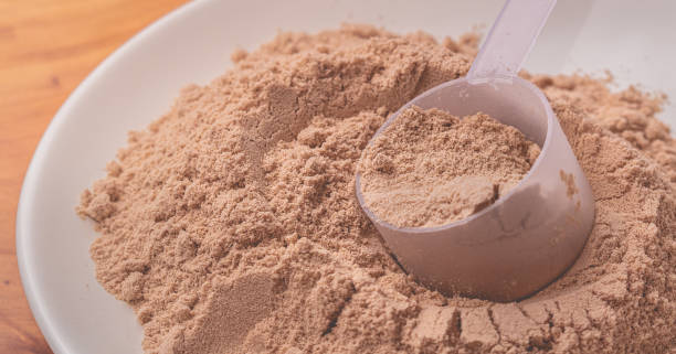 Chocolate flavor whey protein powder in close-up. Chocolate flavor whey protein powder in close-up. proteína stock pictures, royalty-free photos & images