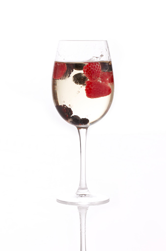 A glass of white sangria with berries.