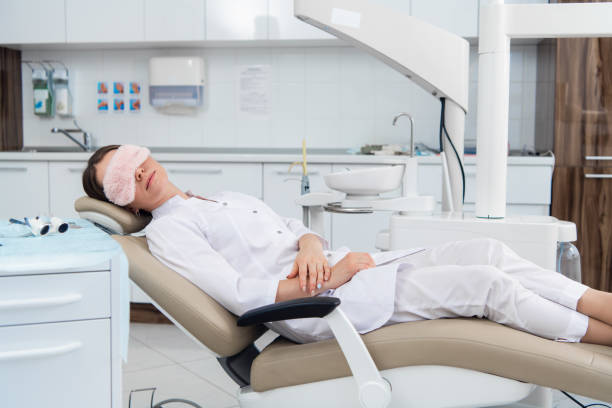 After hours in the dental clinic. A doctor is relaxing in her ch After hours in the dental clinic. A doctor is relaxing in her chair after a tiring day. tablet pc and digital hospital tools stock pictures, royalty-free photos & images