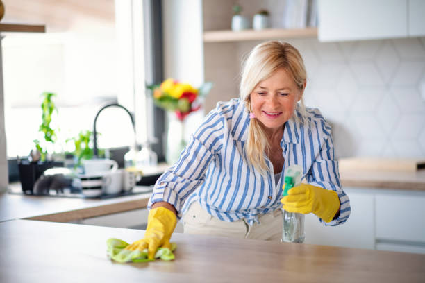 retrato de la mujer mayor limpiando el mostrador de la cocina en el interior en casa. - cleaning domestic kitchen counter top housework fotografías e imágenes de stock
