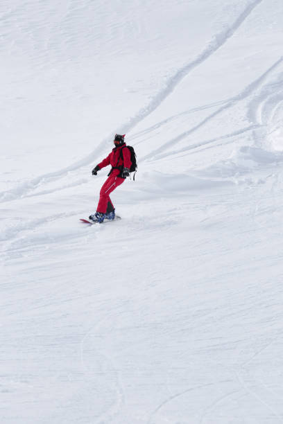 snowboarder em vermelho desce na encosta de esqui nevado - snowboarding snowboard teenager red - fotografias e filmes do acervo