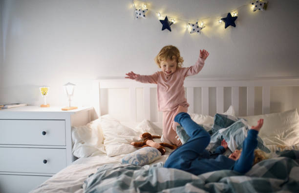 istock Two small children jumping on bed indoors at home, having fun. 1225470519
