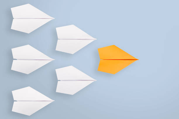 istock Leadership concepts with orange paper airplane leading among white 1225472462