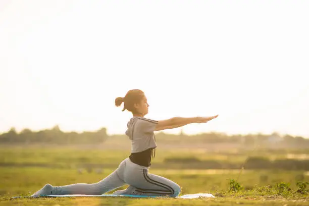 Portrait of a Young Woman performing Yoga outside in sunny bright light.