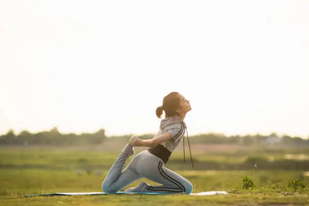 Portrait of a Young Woman performing Yoga outside in sunny bright light.