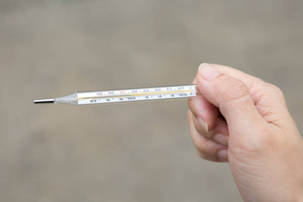 istock A hand holding a thermometer on a Brown background 1225474427