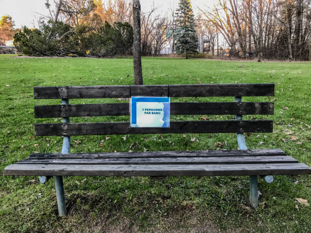 istock Public bench in a park with sign saying one person per bench 1225475353