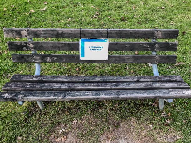 istock Public bench in a park with sign saying one person per bench 1225475375