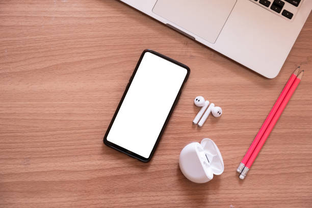 istock Smartphone with blank screen isolate and wireless headphone and laptop on wooden desk. 1225482244