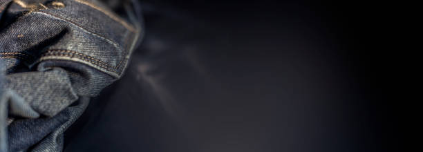 istock Black colored denim jeans material against a black blurred background. 1225494060