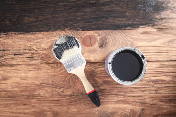 istock Black paint and brush on wooden background. 1225499023