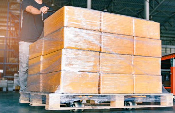 istock Closeup package boxes, Worker working with hand pallet truck unloading shipment goods in warehouse 1225499963