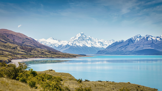 Scenic Panorama of beautiful turquoise Lake Pukaki and snow capped Mount Cook Glacier Mountain Range in Summer. South Island, Canterbury, Mackenzie Basin, Mount Cook, Lake Pukaki, New Zealand