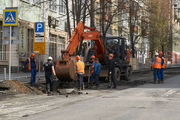Perm, Russia - May 05, 2020: workers gathered around an excavator discuss work on the upcoming trenching on a city street