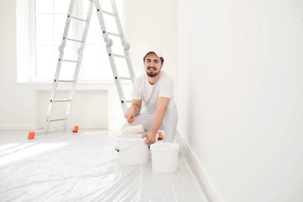 istock A male painter in a white uniform with a roller works in his hand in a white room 1225504611