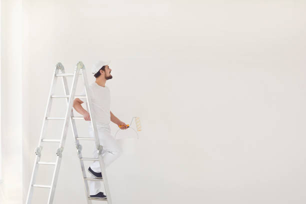 istock A male painter in a white uniform with a roller works in his hand in a white room 1225504614