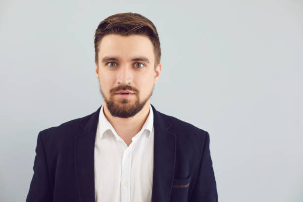 istock Puzzled insecure man in casual jacket on a gray background. Expression of emotion 1225505308