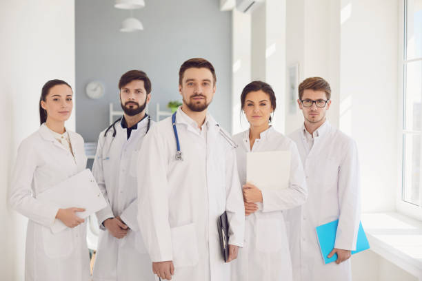 istock A group of confident practicing doctors in white coats are smiling against the backdrop of the clinic. 1225505313