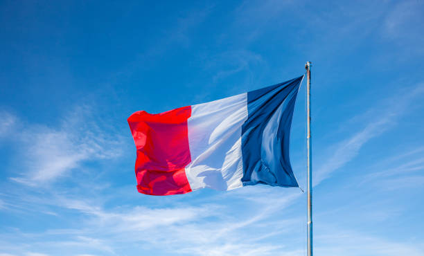 French flag in the wind against a blue sky stock photo