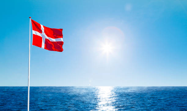 danish flag in the wind against a blue sky - danish flag imagens e fotografias de stock