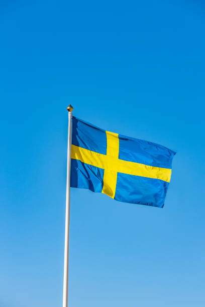istock Swedish flag in the wind against a blue sky 1225505531