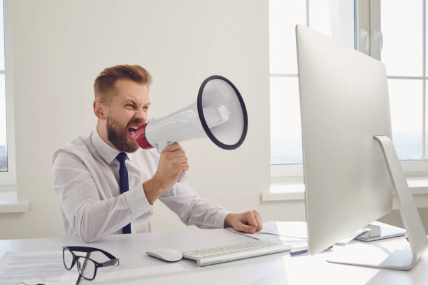 istock Angry displeased boss businessman shouting in megaphone into a computer 1225505553