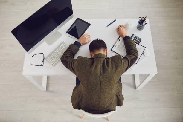 istock Tired exhausted businessman sleeps with stress problems lying at workplace in office. 1225505566