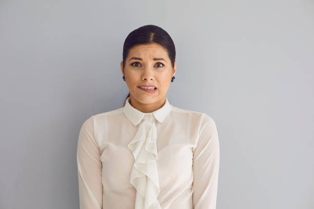 istock Tense young woman looking at camera on gray wall 1225505597
