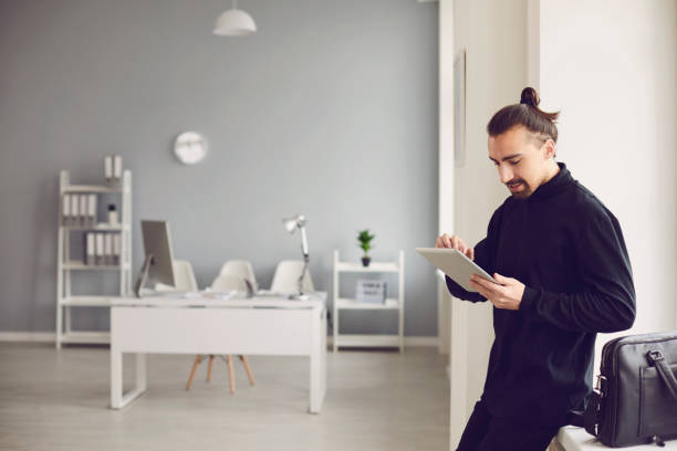 istock A serious guy is standing with a tablet in his hand while standing in the office at the workplace. 1225505682