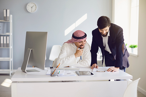 Arab and european businessman confident working in a white office. Businesspeople work startup business project merge business meeting in a modern business center.
