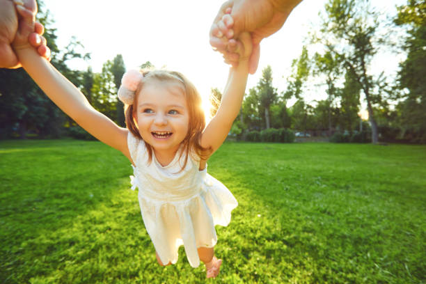 istock Happy child is twisted by hands in the park. 1225508253